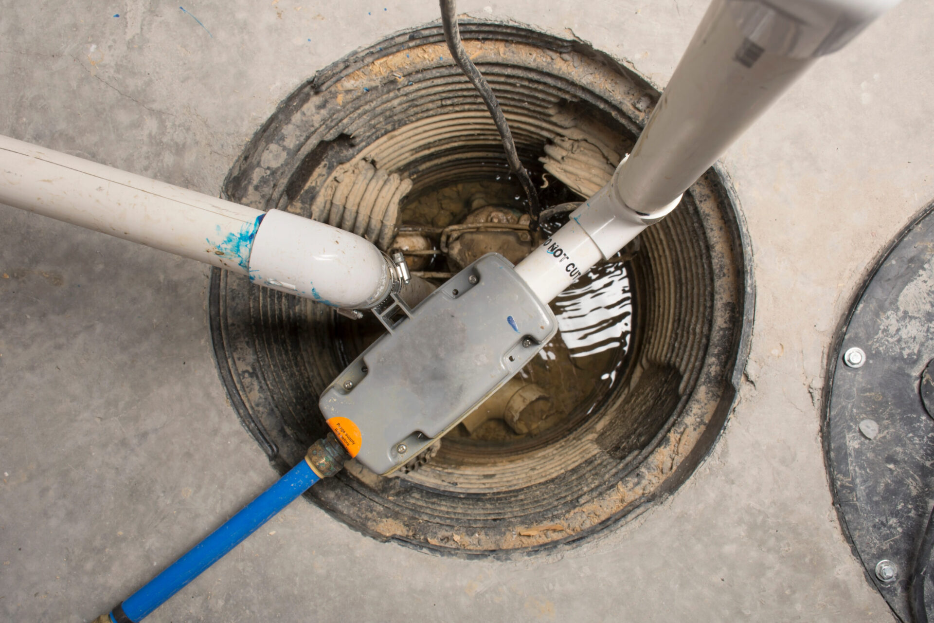 a manhole with a blue hose connected to it