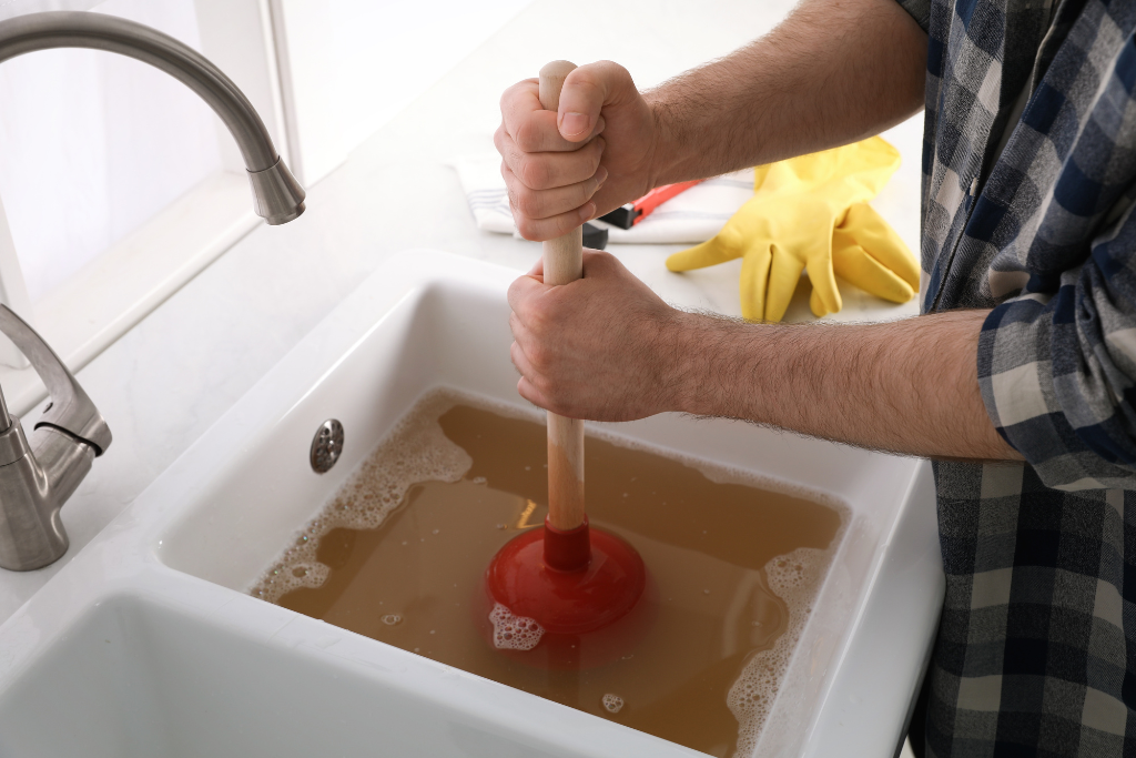 a man plunging a clog in a sink