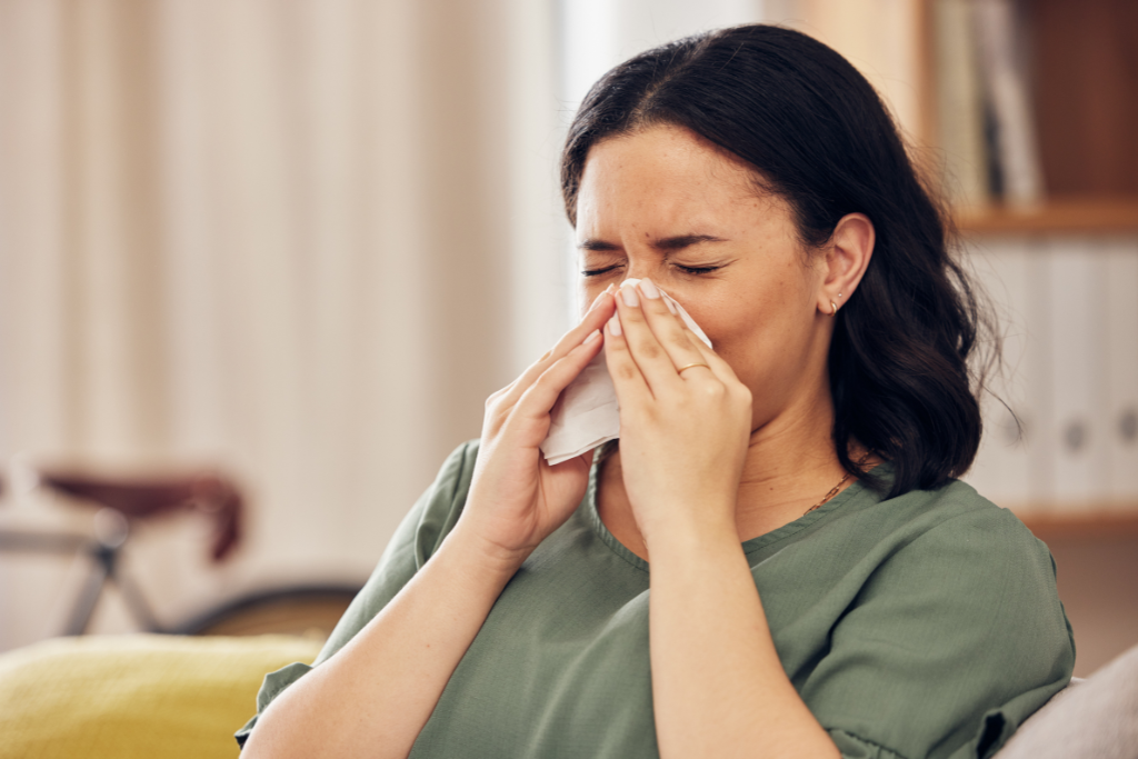 a woman sitting on a couch blowing her nose