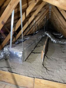 a attic with exposed insulation and wooden beams